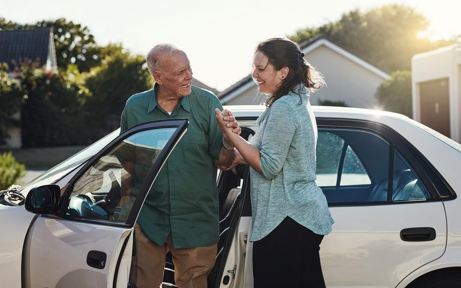 A caregiver helping a client home after a car ride