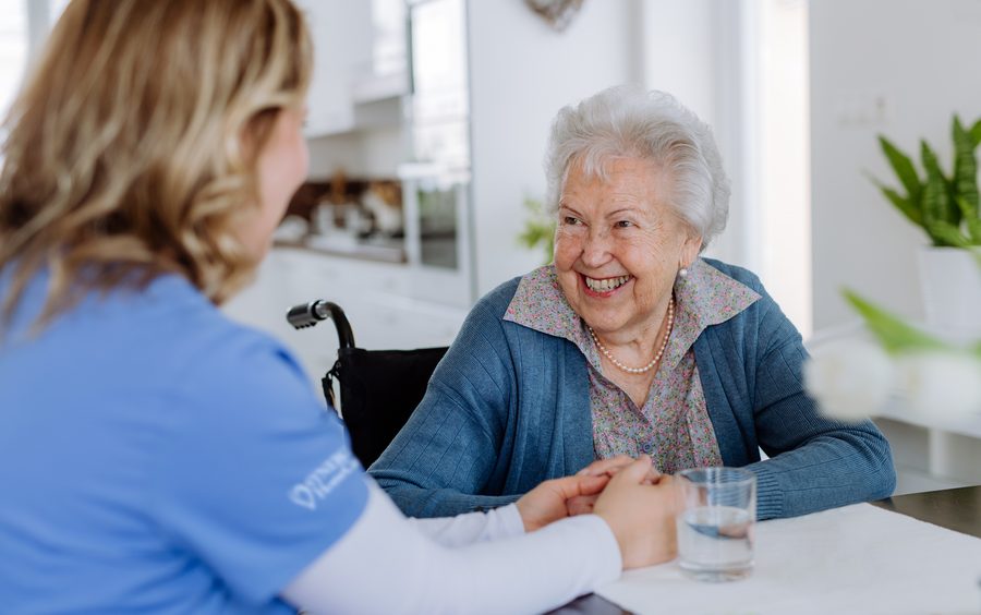 A caregiver holding hands with a client at home