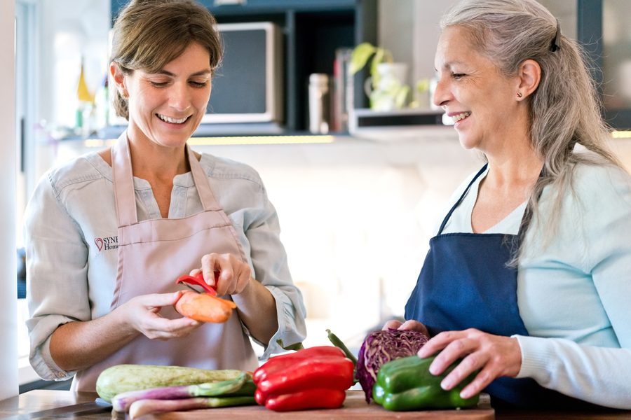 A caregiver and client preparing fresh vegetables together